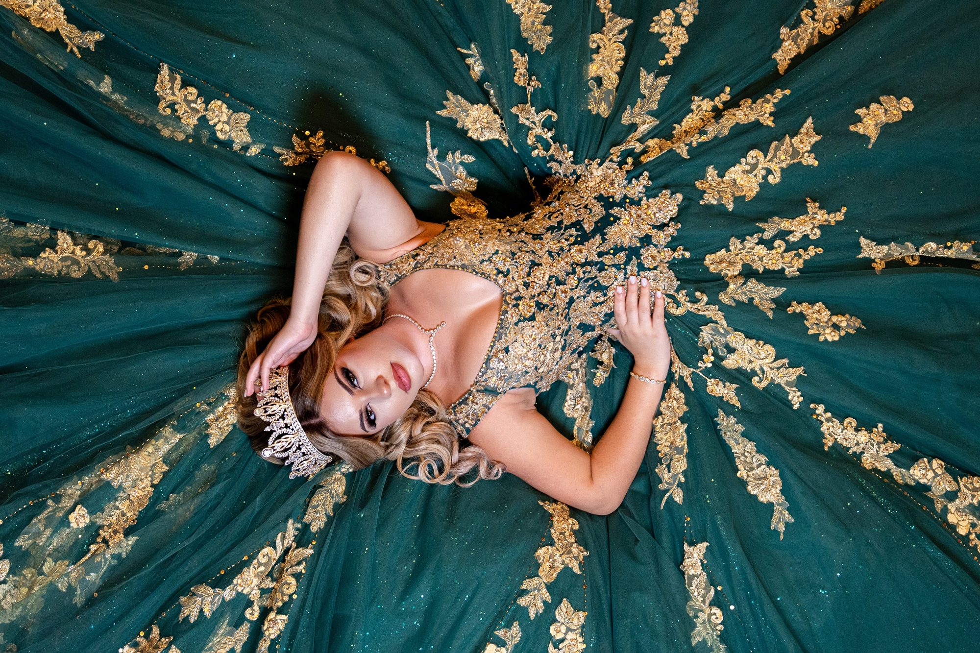 Overhead portrait of a quinceañera in an emerald and gold gown