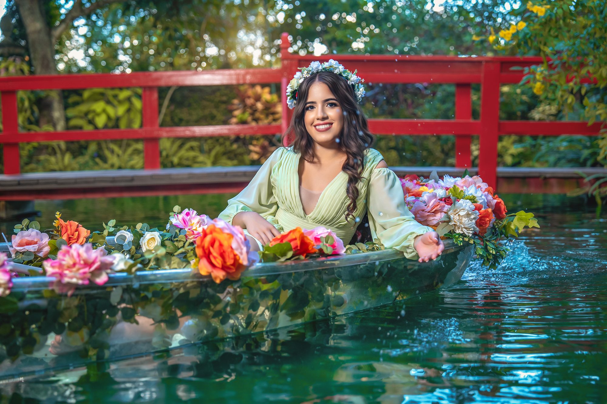 Quinceañera in a flower-filled boat beside a red Japanese bridge