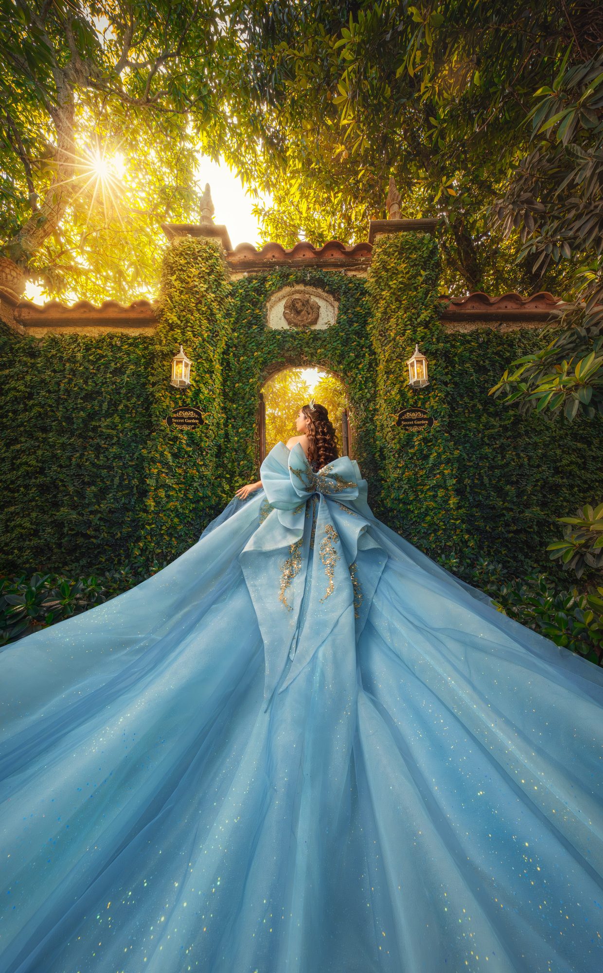 Quinceañera in an ice-blue ball gown under a glowing ivy archway