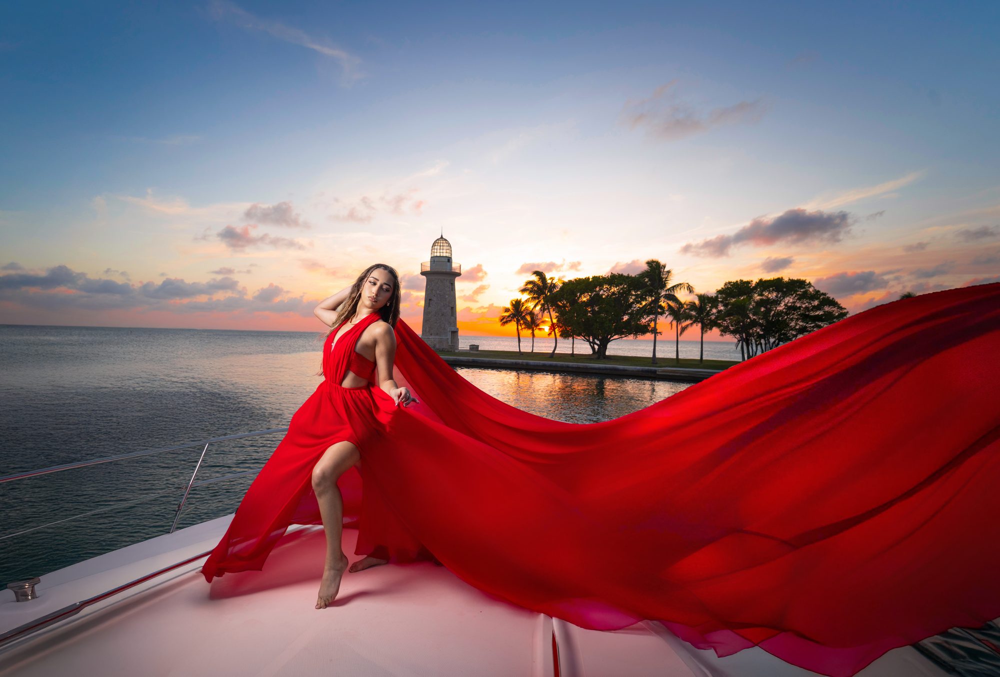 Quinceañera in a red flying dress on a yacht at sunset, Biscayne Bay