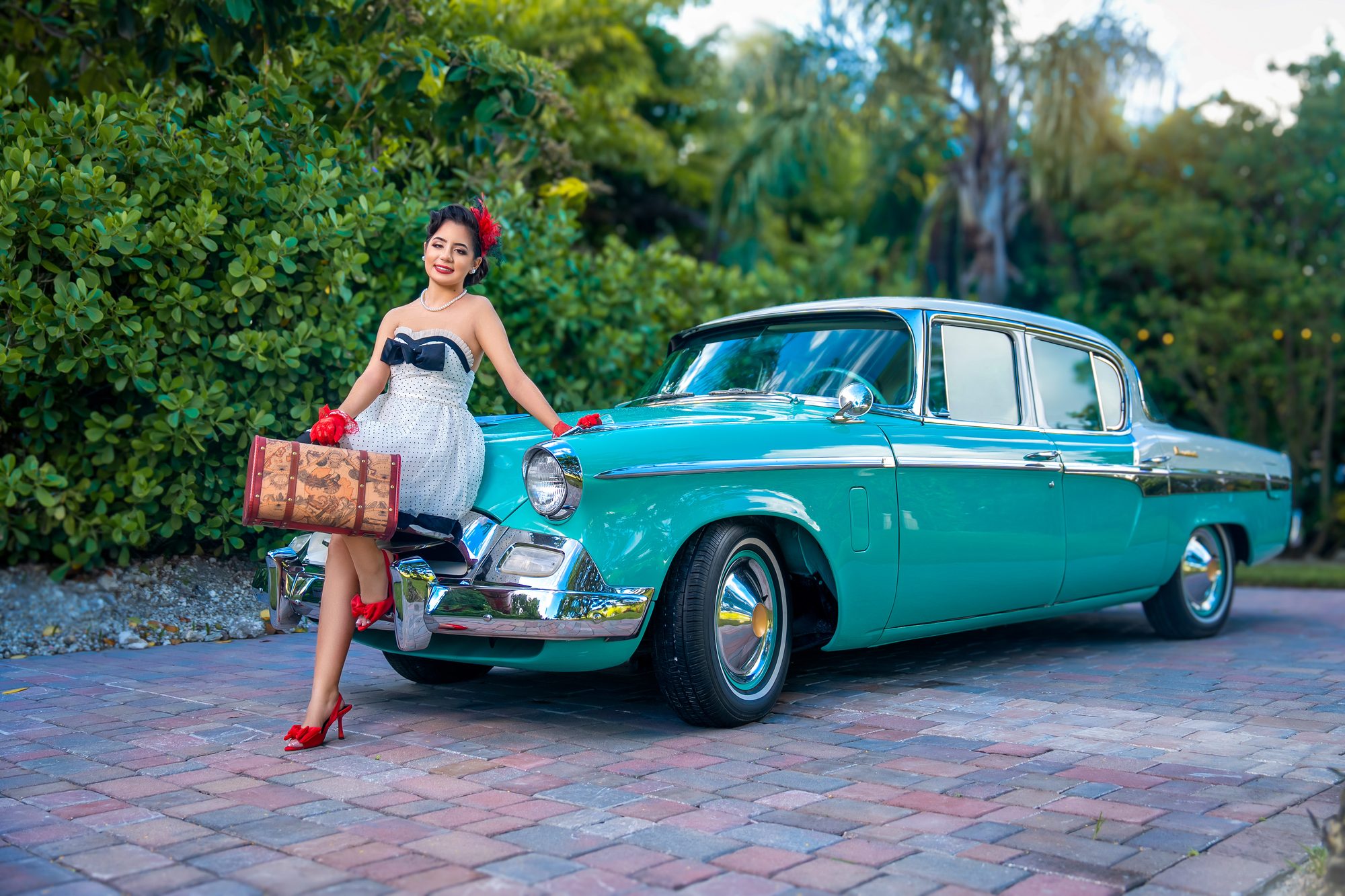 Quinceañera with a vintage turquoise car in a tropical garden, Miami